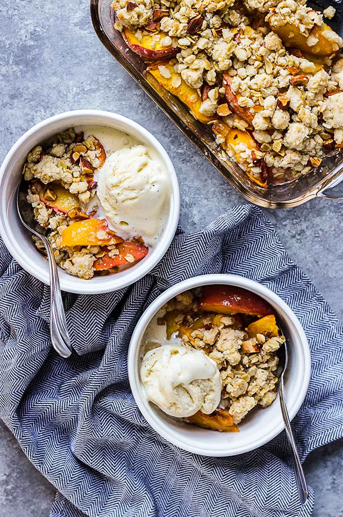 ginger peach crisp in small ramekins with spoon.