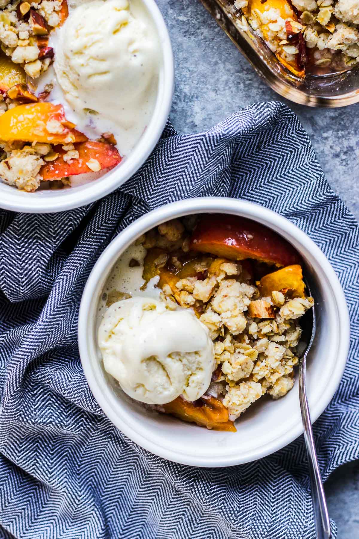 vegan ginger peach crisp close up in ramekin with a blue napkin.