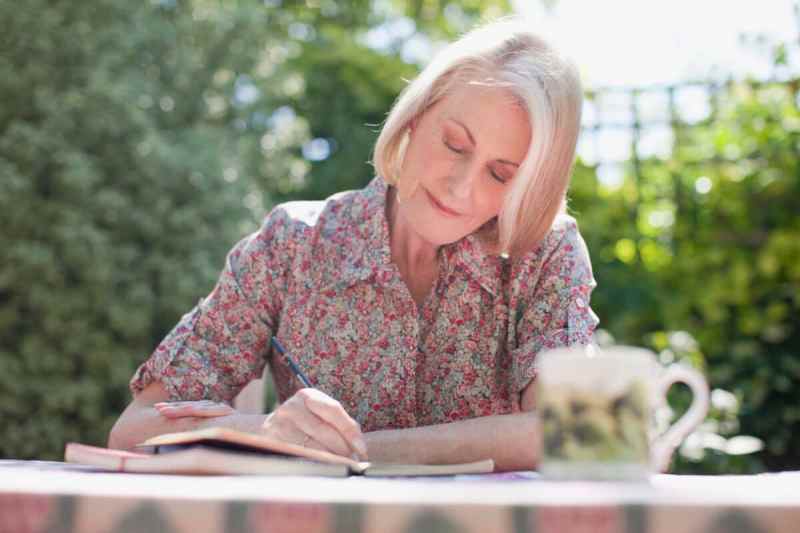 Woman writing in journal at patio table