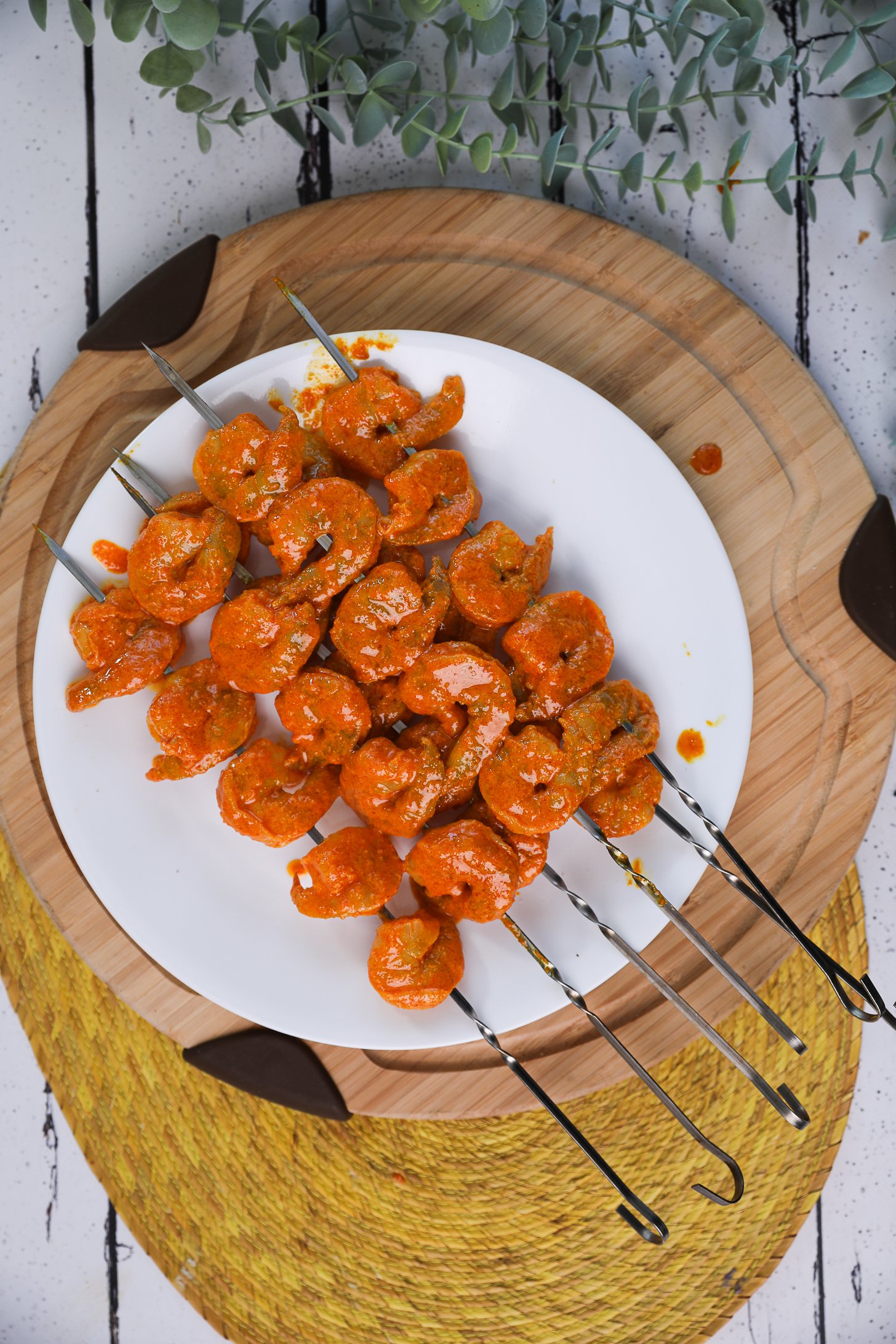 A pile of spice-coated shrimp skewers on a plate.