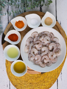 A selection of food ingredients including raw shrimp and powdered spices.