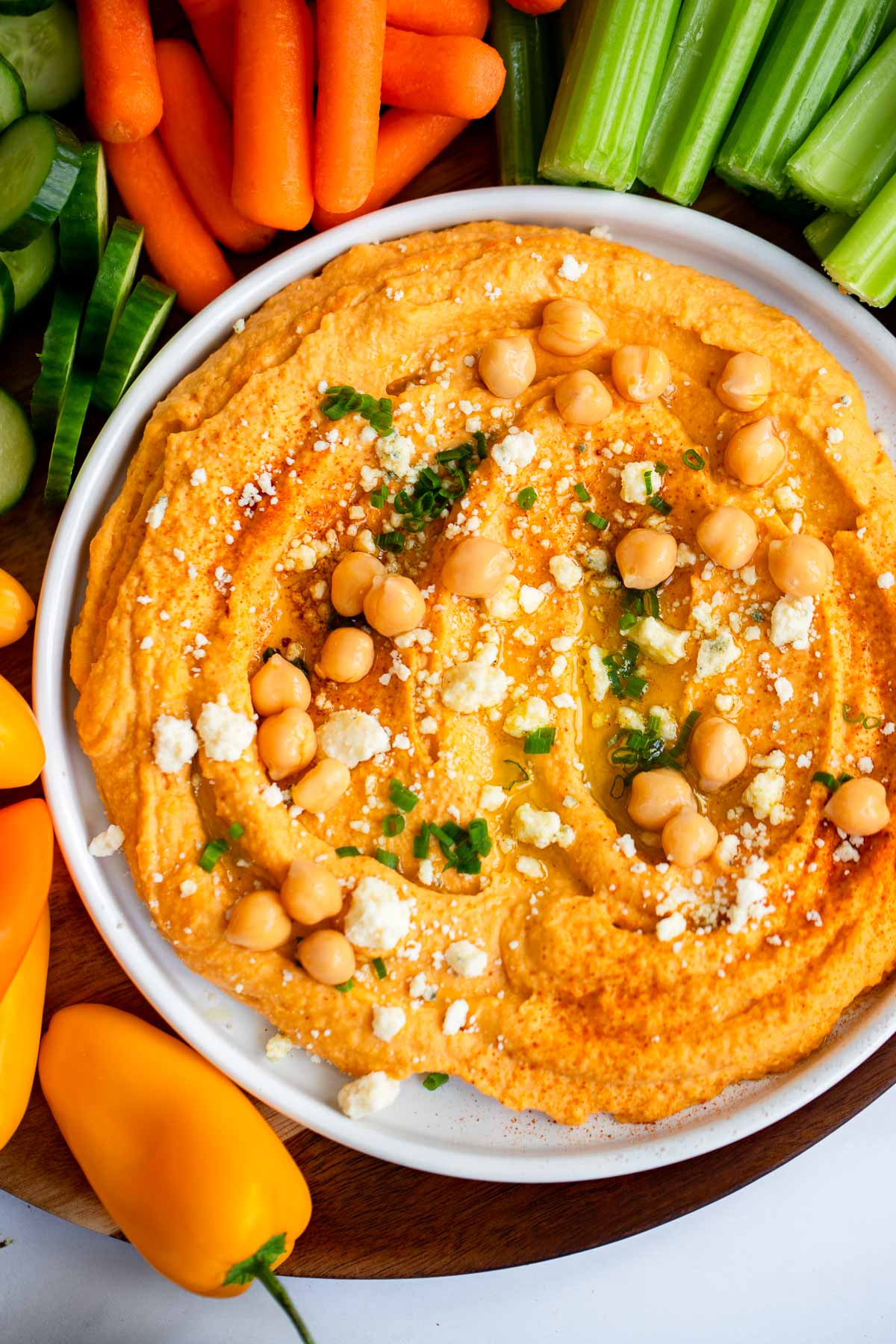 close up shot of buffalo hummus topped with blue cheese, chickpeas, and chives. 