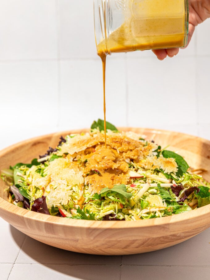 hand pouring dressing on crispy rice and brussels sprouts salad