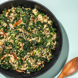 kale, lentil and quinoa salad in black bowl with wooden spoon