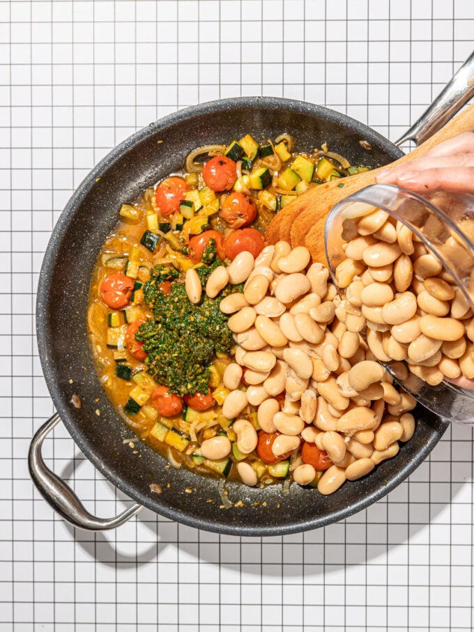 Hand adding beans to skillet